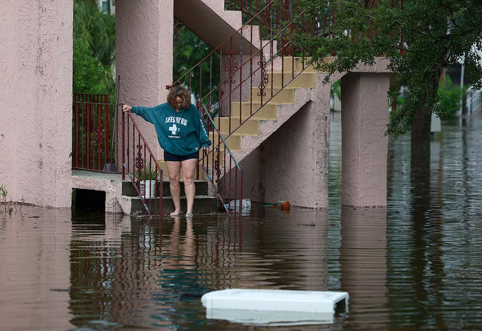 A woman looks out at the flood waters from Hurricane Idalia surrounding her apartment complex on 30 August 2023 in Tarpon Springs, Florida