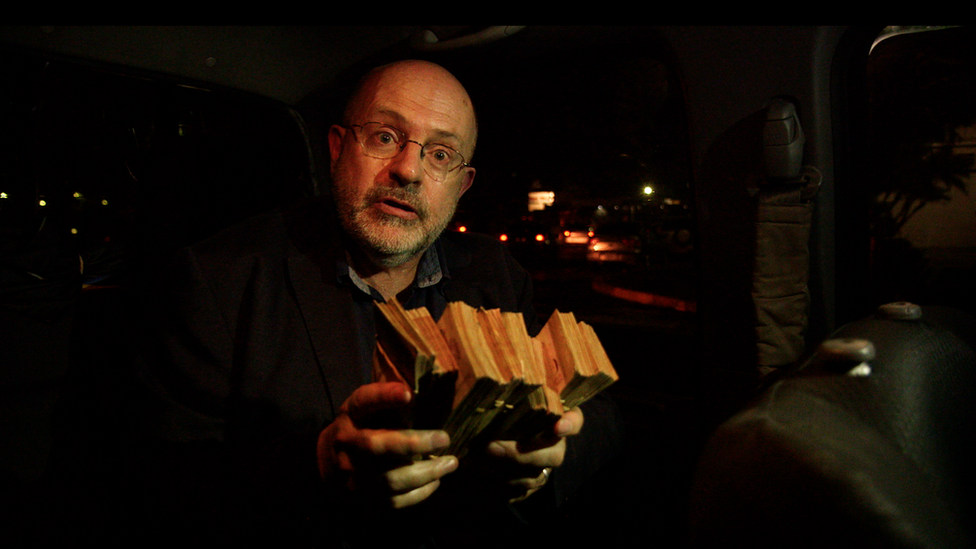 John Sweeney holds a stack of Venezuelan Bolivars