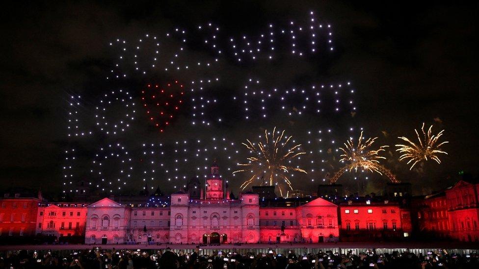 Drones spelling out "2023 with love from London" in the sky above the city as fireworks exploded behind them