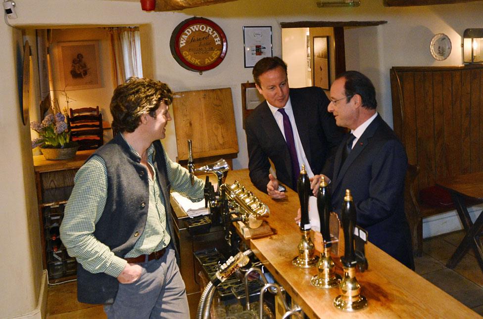 David Cameron and France's President Francois Hollande stand at the bar with landlord Archie Orr-Ewing at The Swan Inn in 2014