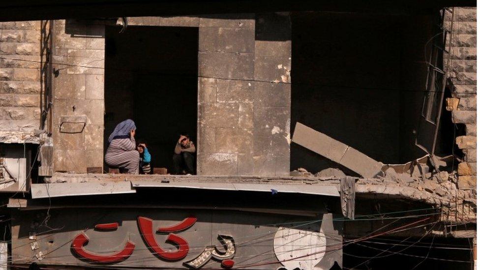 Civilians sit inside a damaged house in a government held area of Aleppo, Syria on 9 December 2016.