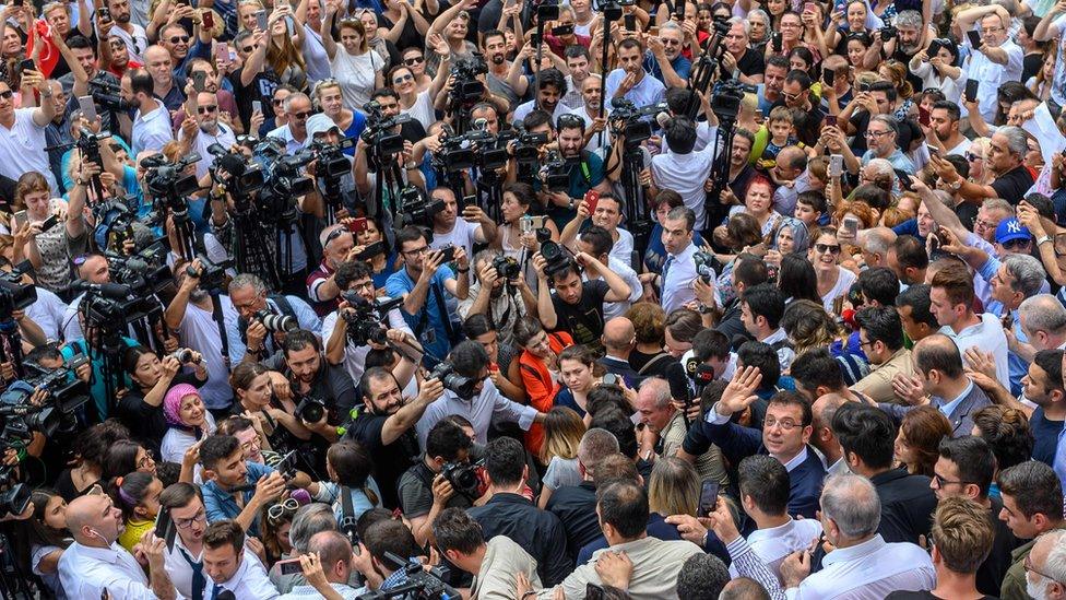 Opposition candidate Ekrem Imamoglu (lower right, looking towards camera) waves after leaving polling station - 23 June