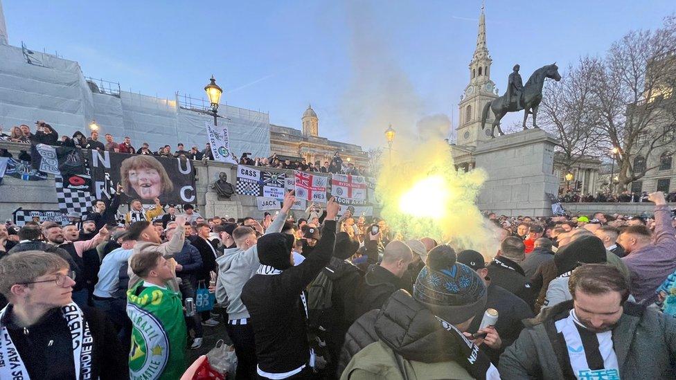 Someone lights a flare among a large crowd of people