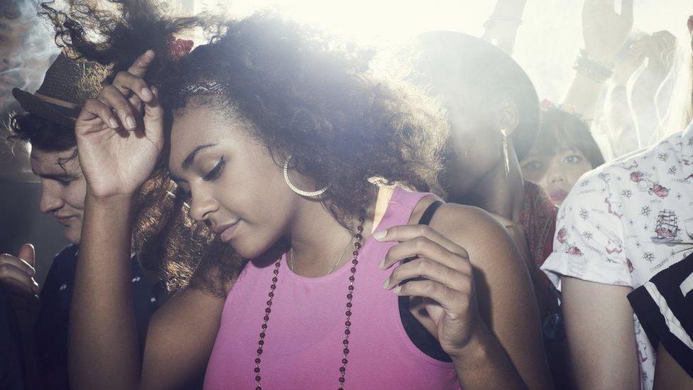 A girl dancing with a group of people in a nightclub