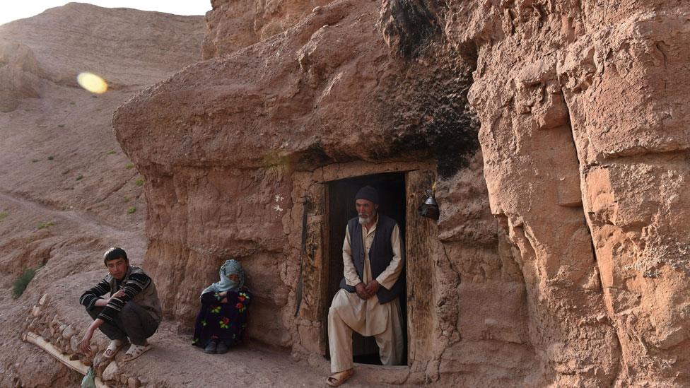 A Hazara Afghan family look on in front of their cave in the old city of Bamiyan