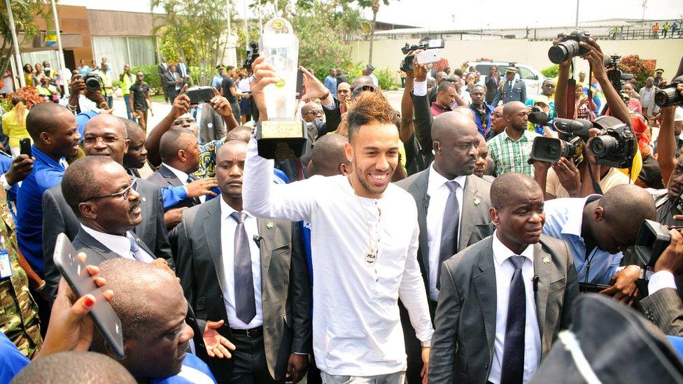 Pierre-Emerick Aubameyang, newly-crowned African Player of the Year, walks among a large crowd holding up his trophy in Libreville, Gabon