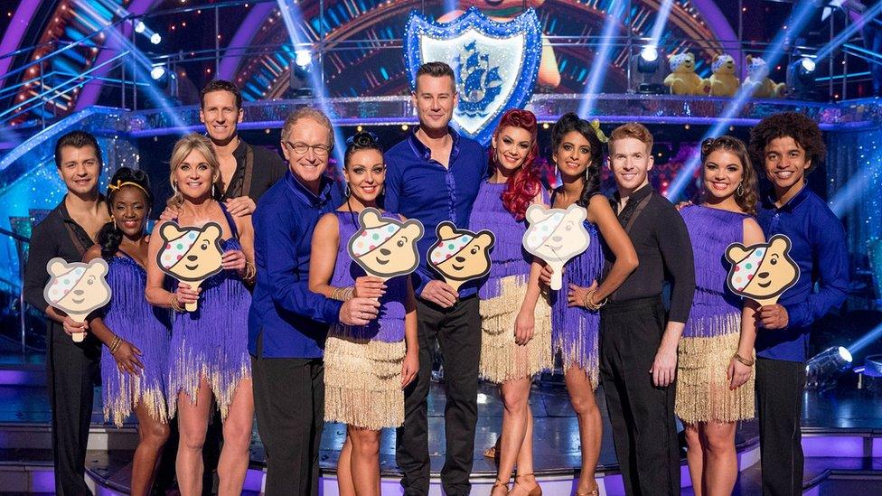 Blue Peter presenters line up with their Strictly partners, holding paddles with Pudsey's face on them