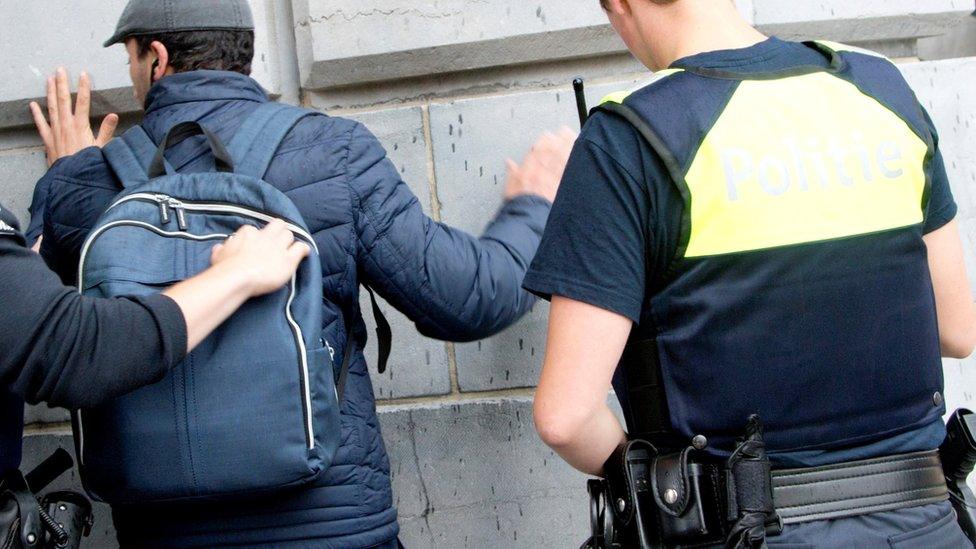 Police search a man's backpack at a station in Antwerp, 18 June