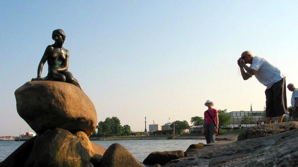 A man photographs the Little Mermaid statue in Copenhagen