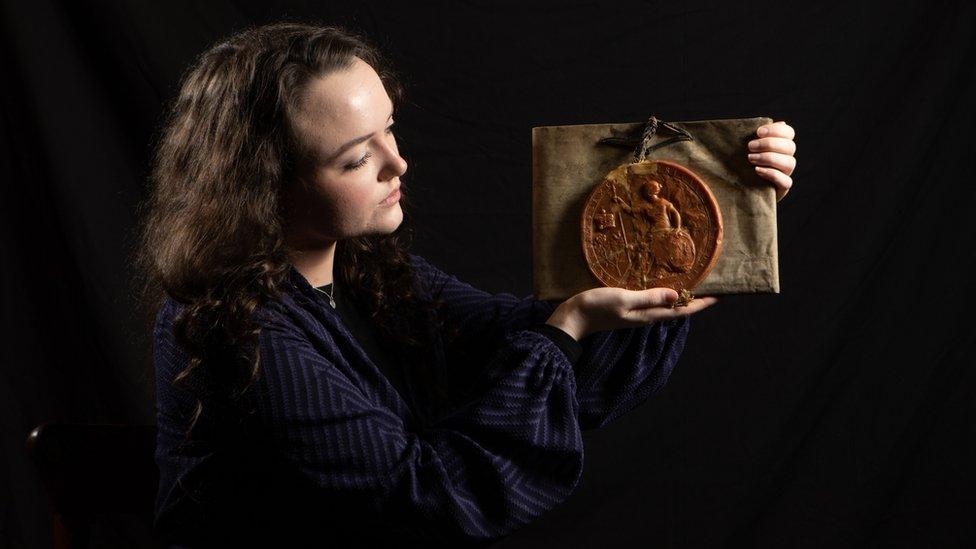 A woman holds an artefact in her hands