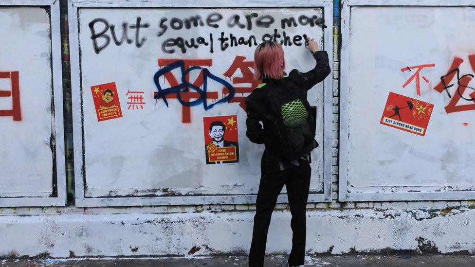 Pro-democracy activists and graffiti artists write over the Chinese slogans