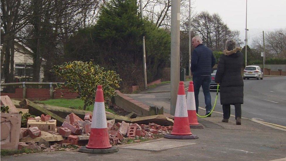 residents walk past debris