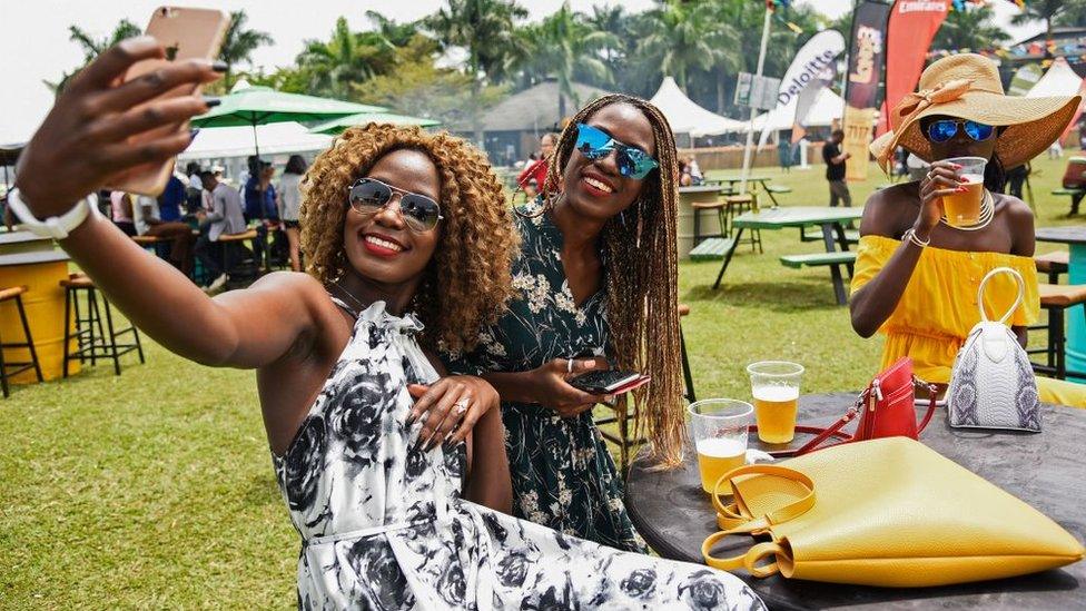 Women take selfie pictures with their mobile phone during the Royal Ascot Goat Races in Kampala, Uganda, on August 25, 2018.