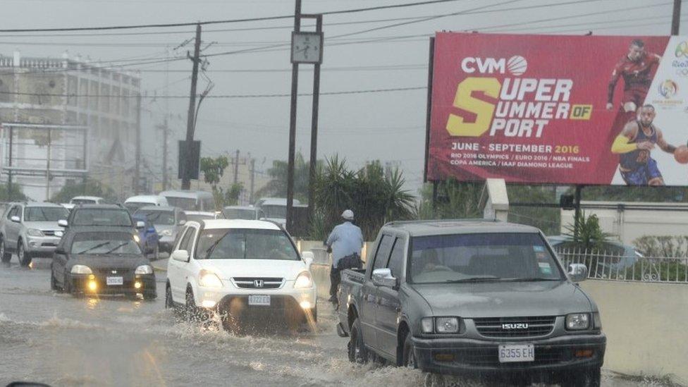 Cars drive along a street under heavy rain in downtown Kingston (02 October 2016)