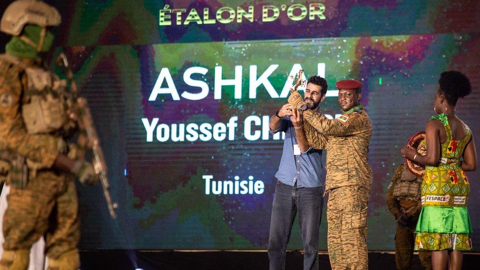 A man representing Youssef Chebbi collects the award on his behalf from Interim Burkina Faso President Ibrahim Traoré.