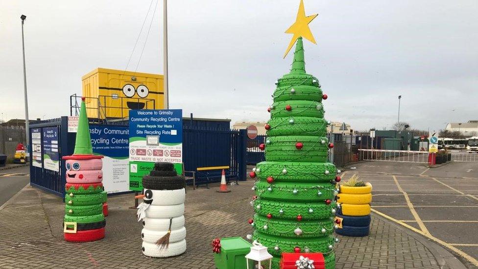 Discarded tyres stacked up on top of each other and painted to look like a Christmas tree, snowman and elf