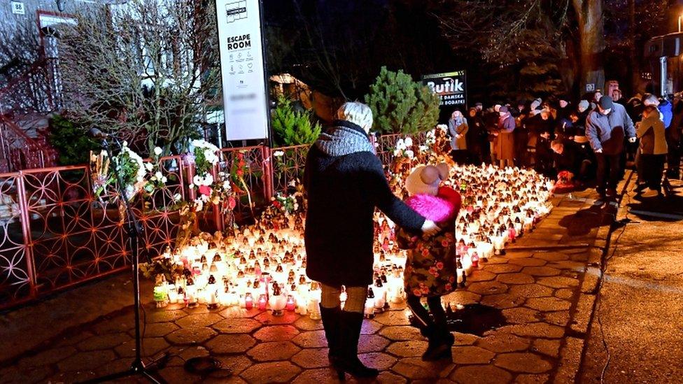 People lay flowers and candles at the site of the Escape Room fire tragedy in Koszalin, Poland, on 6 January 2019