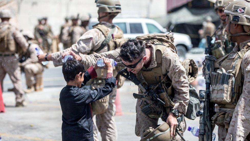 A US Marine and a child spray water at each other during an evacuation at Hamid Karzai International Airport, Kabul, Afghanistan, 21 August 2021