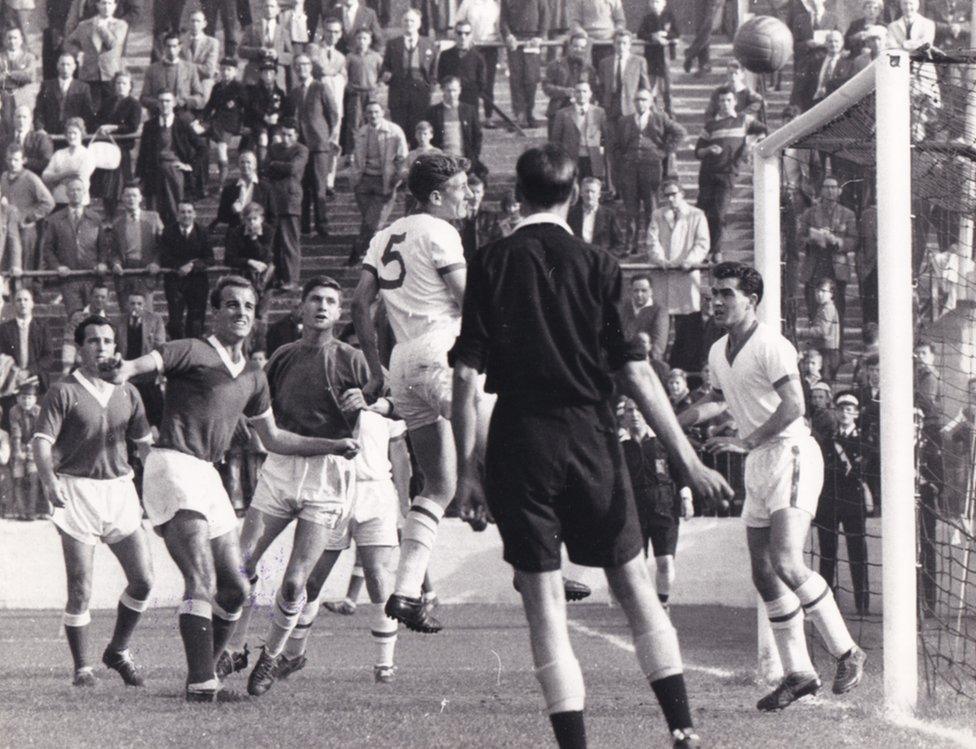 Players in a penalty area jostle for the ball