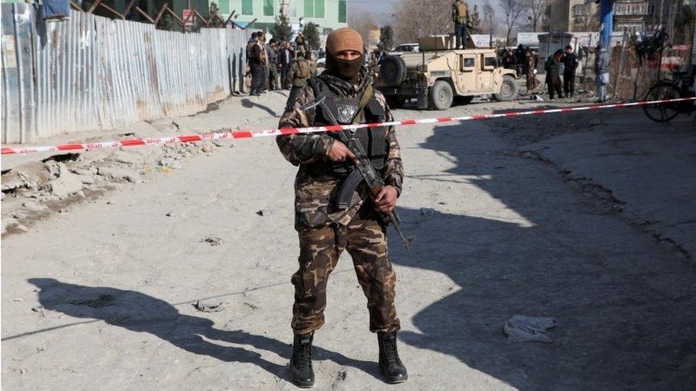 An Afghan security officer stands guard at the site of a bomb blast in Kabul