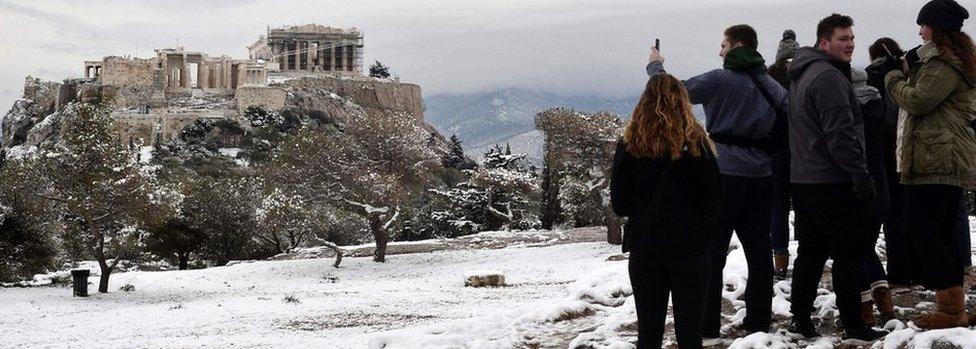 Foreign students take pictures of the snow-covered Acropolis (C) from the Pnyx hill in Athens, after a rare heavy snowfall on the city, on January 10, 2017