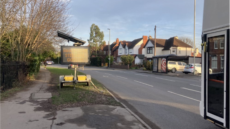 A stretch of road in Longlevens, with houses nearby