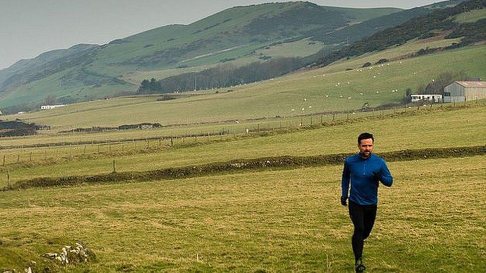 Richard Harrington running in countryside with hilly backdrop