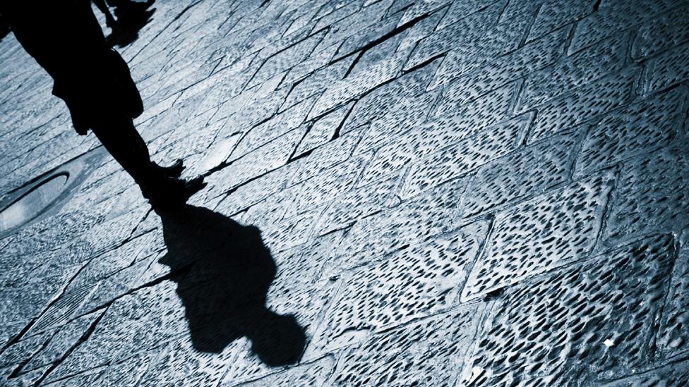 Shadow of man standing on pavement after dark