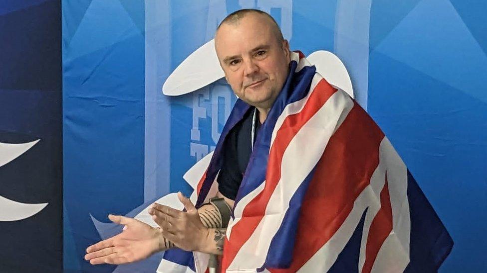 Mr Cresswell clapping poolside draped in a union flag after taking a silver and bronze for swimming at the US Air Force Warrior Games Trials