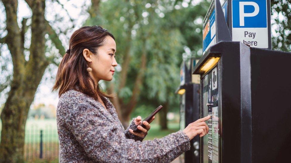 Woman using a car park ticket machine