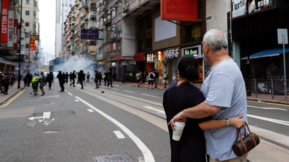 A couple hugs each other as police fire tear gas into the crowds to disperse anti-national security law protesters during a march at the anniversary of Hong Kong"s handover to China from Britain in Hong Kong, China