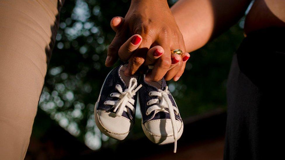 A couple holds shoes meant for a baby