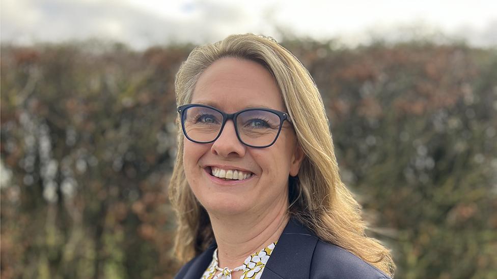 Woman with long blond hair and glasses