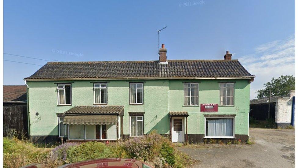 Green-coloured two-storey house with long thin windows