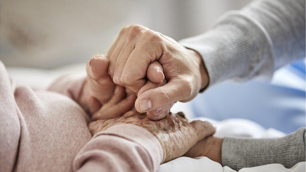 Carer holding hands with elderly person