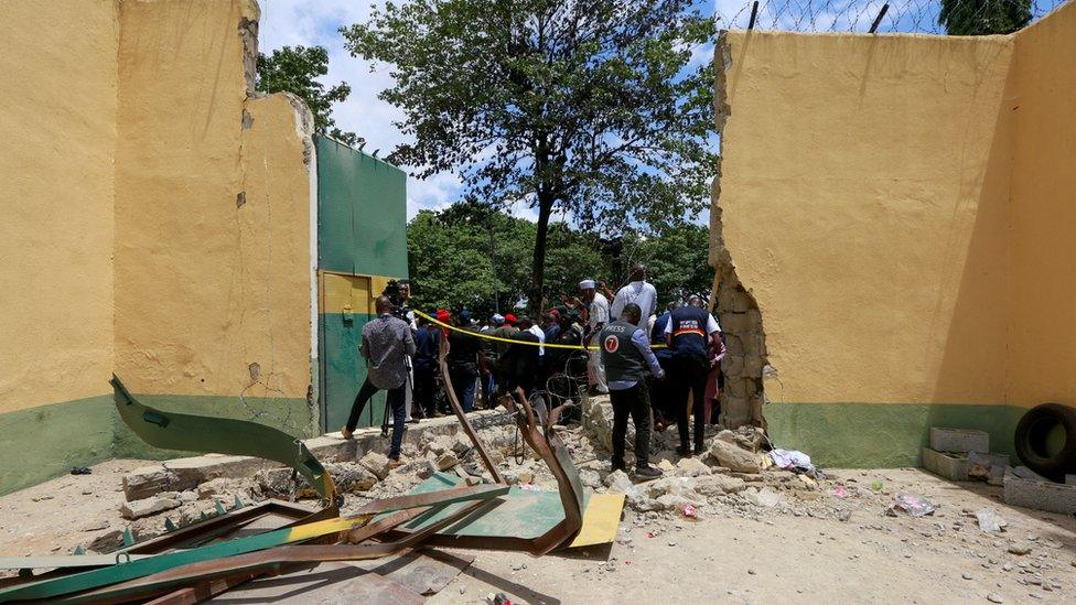 People stand outside the main door of Kuje Medium prison on 6 July after it was destroyed during the attack