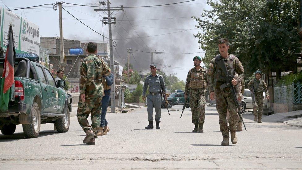 Afghan security officials secure the road outside the scene of the attack