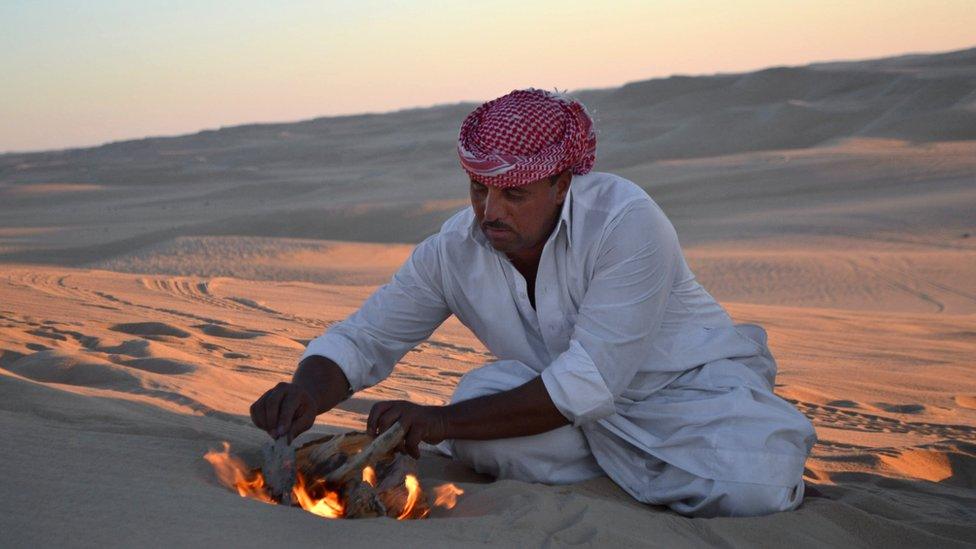 File picture of desert safari driver building a small fire to make mint tea before sunset during a trek through the Great Sand Sea outside the Egyptian oasis of Siwa
