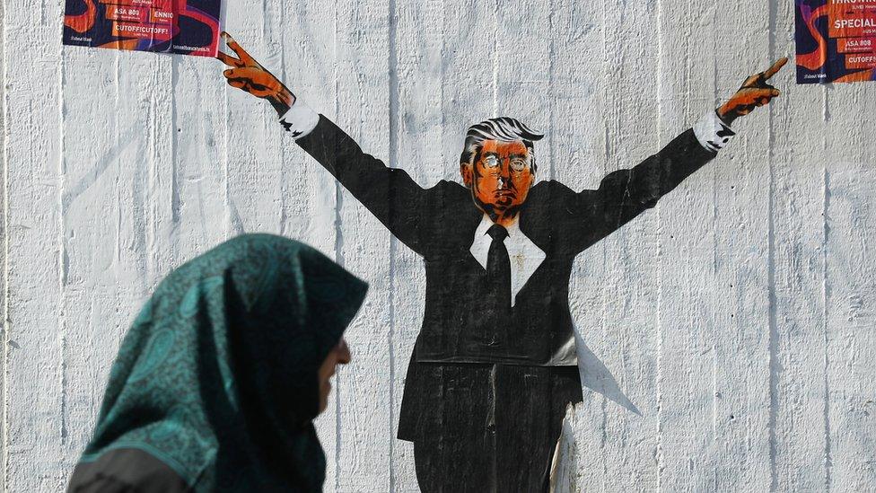 A Muslim woman walks past a street artist's rendition of U.S. President Donald Trump on 27 June, 2017 in Berlin, Germany