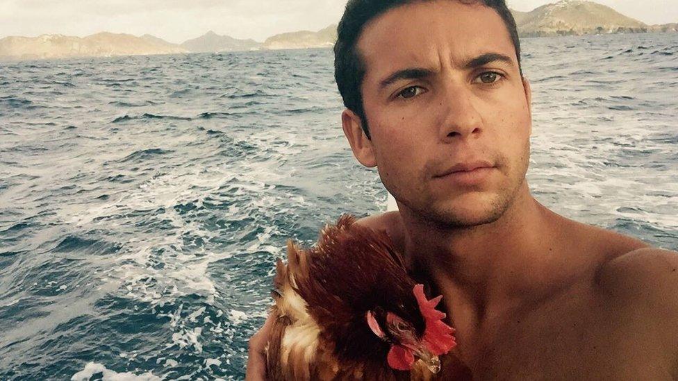 Sailor Guirec Soudee holding his hen MOnique on the deck of a yacht