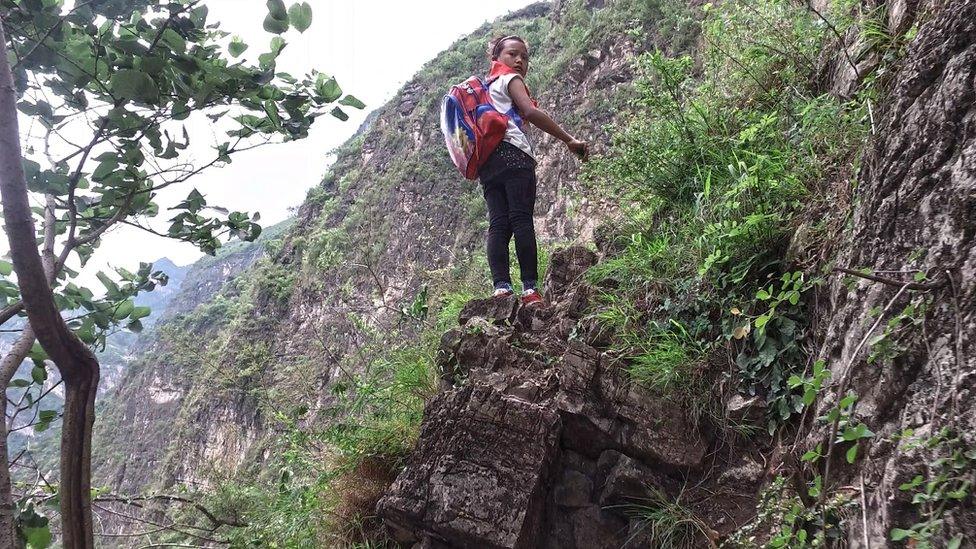 A girl of Atuler Village looks back during climbing a cliff on her way home in Zhaojue county in southwest China's Sichuan province on May 14, 2016 in Zhaojue, China.