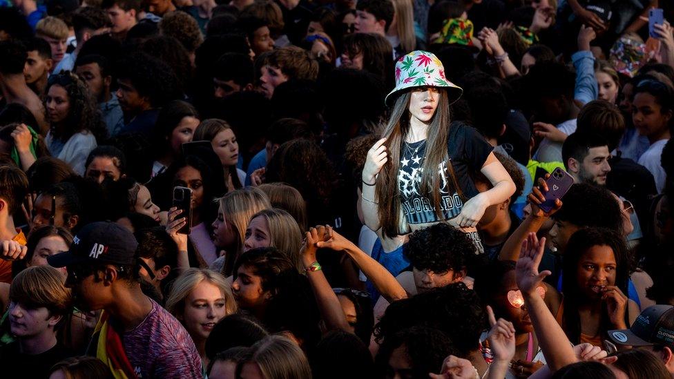 woman in hat elevated above a large packed crowd