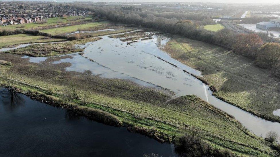 Drone shot of a triangular area of water with houses in the background