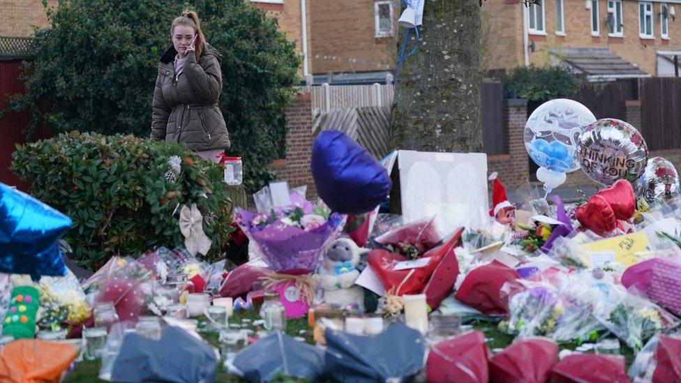 A woman lays flowers among the tributes near to Babbs Mill Park in Kingshurst, Solihull, after the deaths of three boys aged eight, 10 and 11 who fell through ice into a lake in the West Midlands.