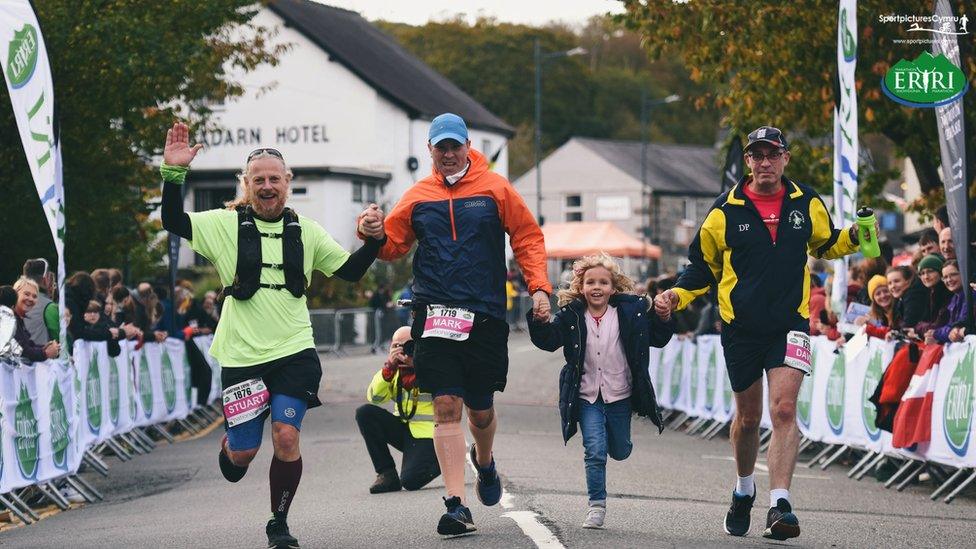 Roedd un ferch fach yn helpu Stuart, Mark a Daniel i gyrraedd y llinell derfyn