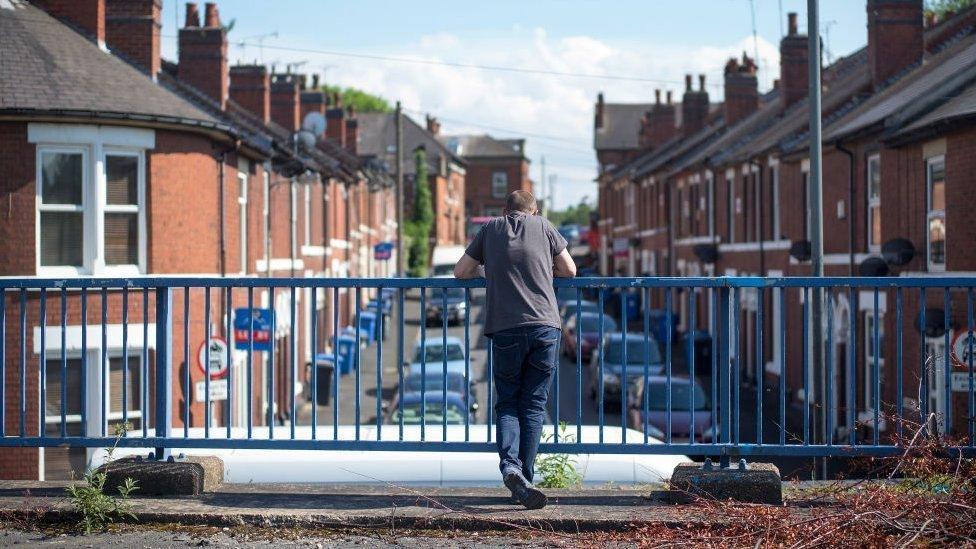 Man peers out over terraced street