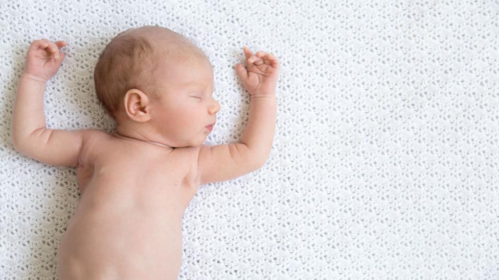 baby lying asleep on mattress, face up