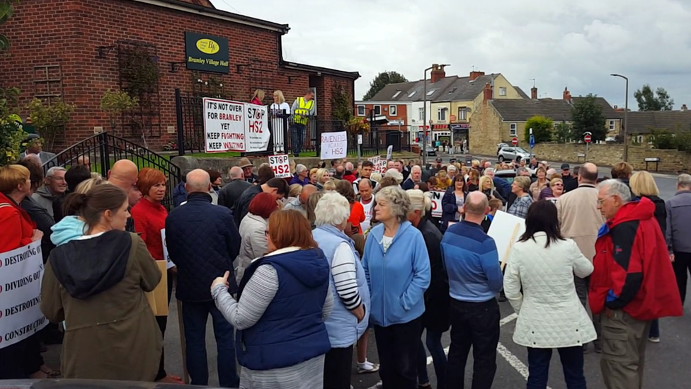 People with placards gathering outside a village hall