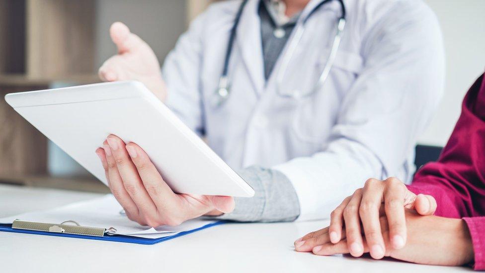 A doctor shows a patient medical information on a tablet computer