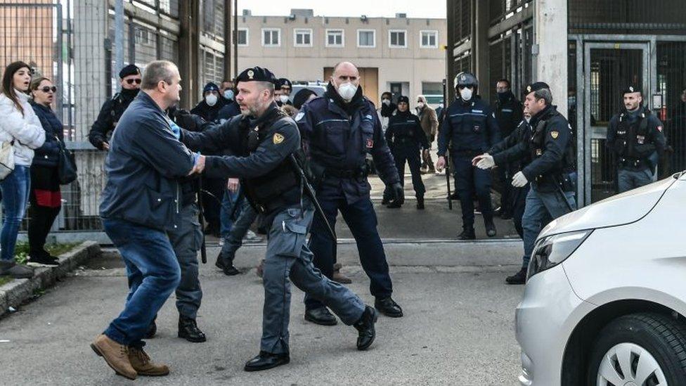 A man is restrained by a police officer outside a prison in Modena, Italy. Photo: 9 March 2020